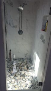 A shower with marble walls and floor in the bathroom.