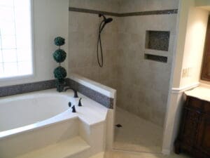 A bathroom with a walk in shower and a tub.